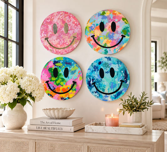 Four colorful 12-inch round original smiley face paintings from Kate McNamee Art displayed together in a bright, neutral home interior.