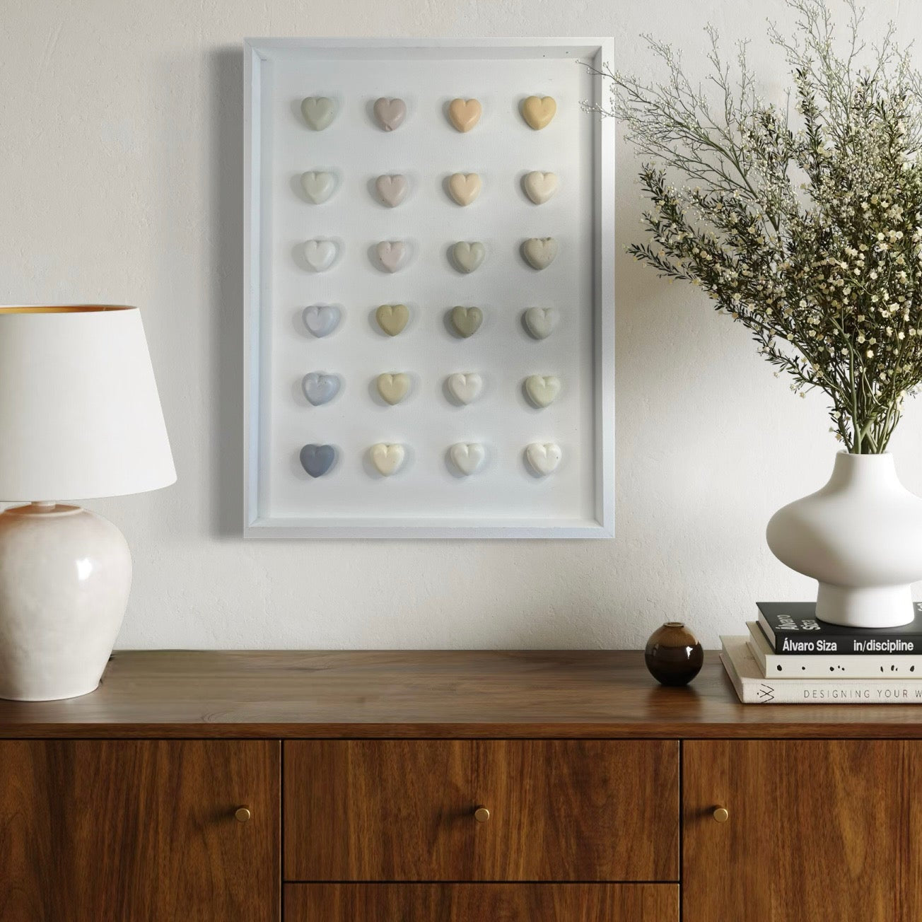 Framed art piece on a wall above a wooden sideboard with decor items.
