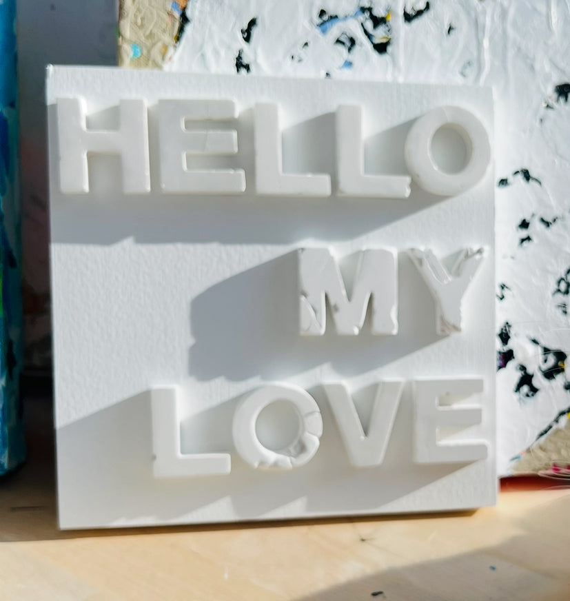 White 3D text sculpture with 'HELLO MY LOVE' on a textured surface