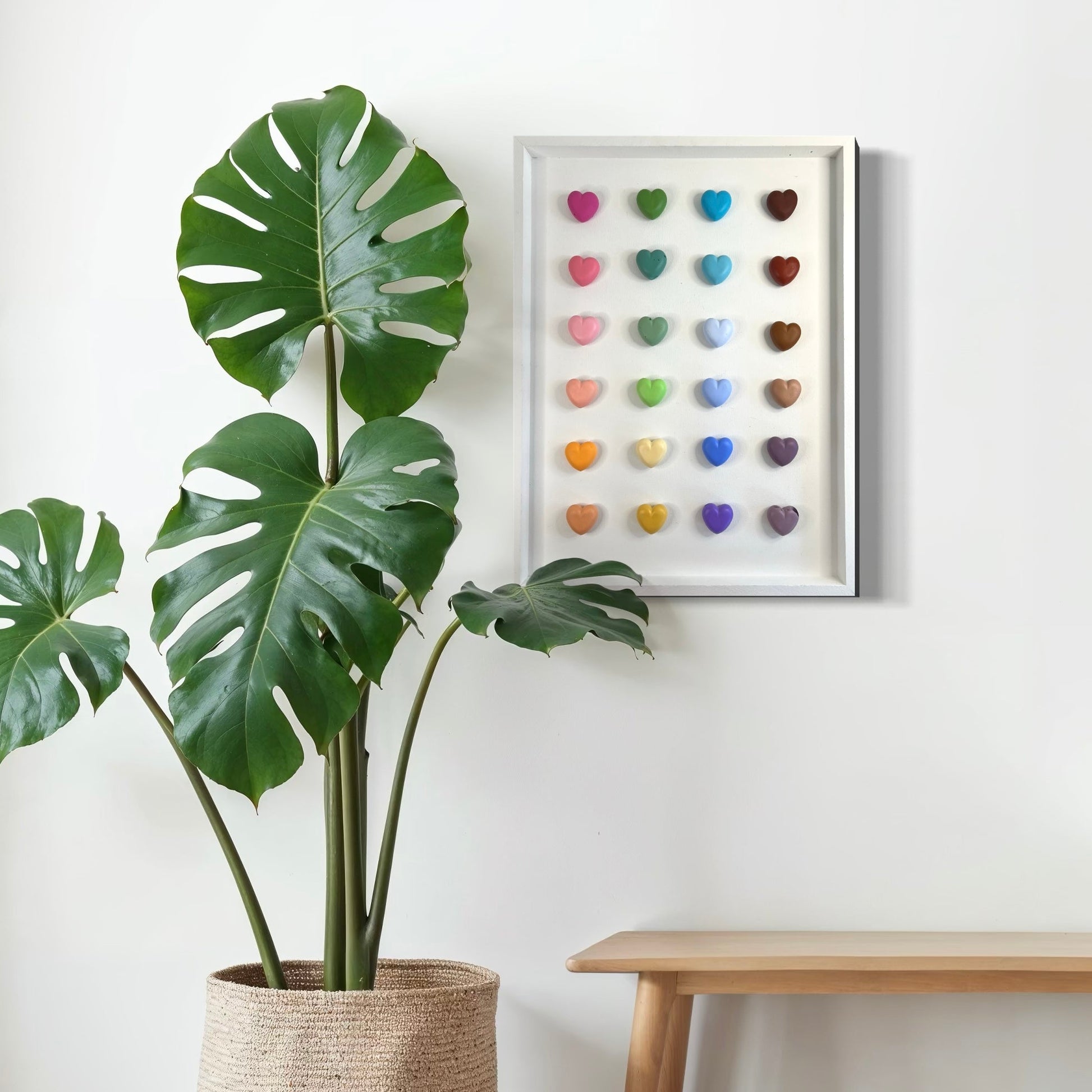 Potted plant next to a wall with a colorful heart art piece and a wooden bench.