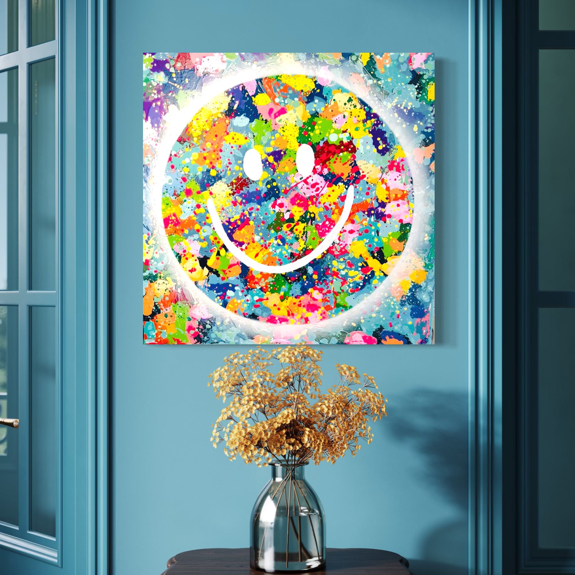 Colorful smiley face painting on a blue wall with a vase of flowers below.