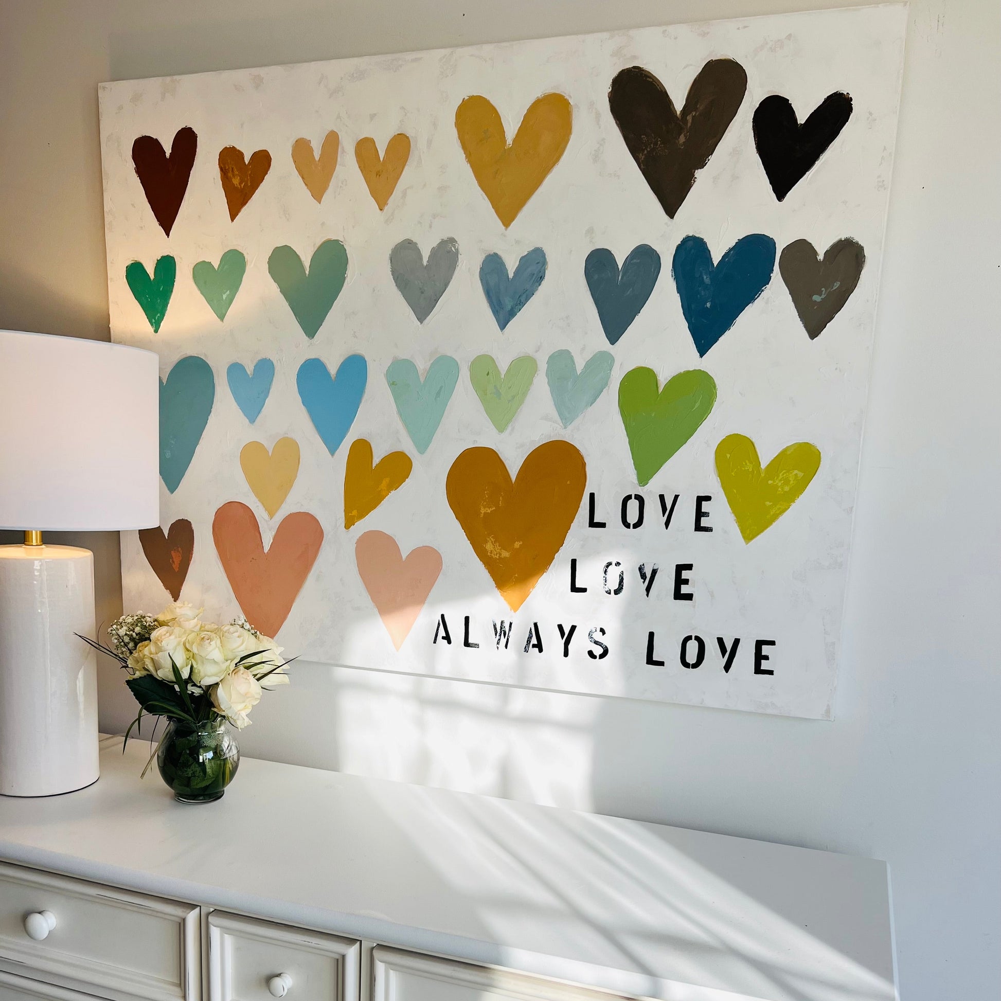 Decorative wall art with colorful hearts and 'LOVE' text above a white dresser.
