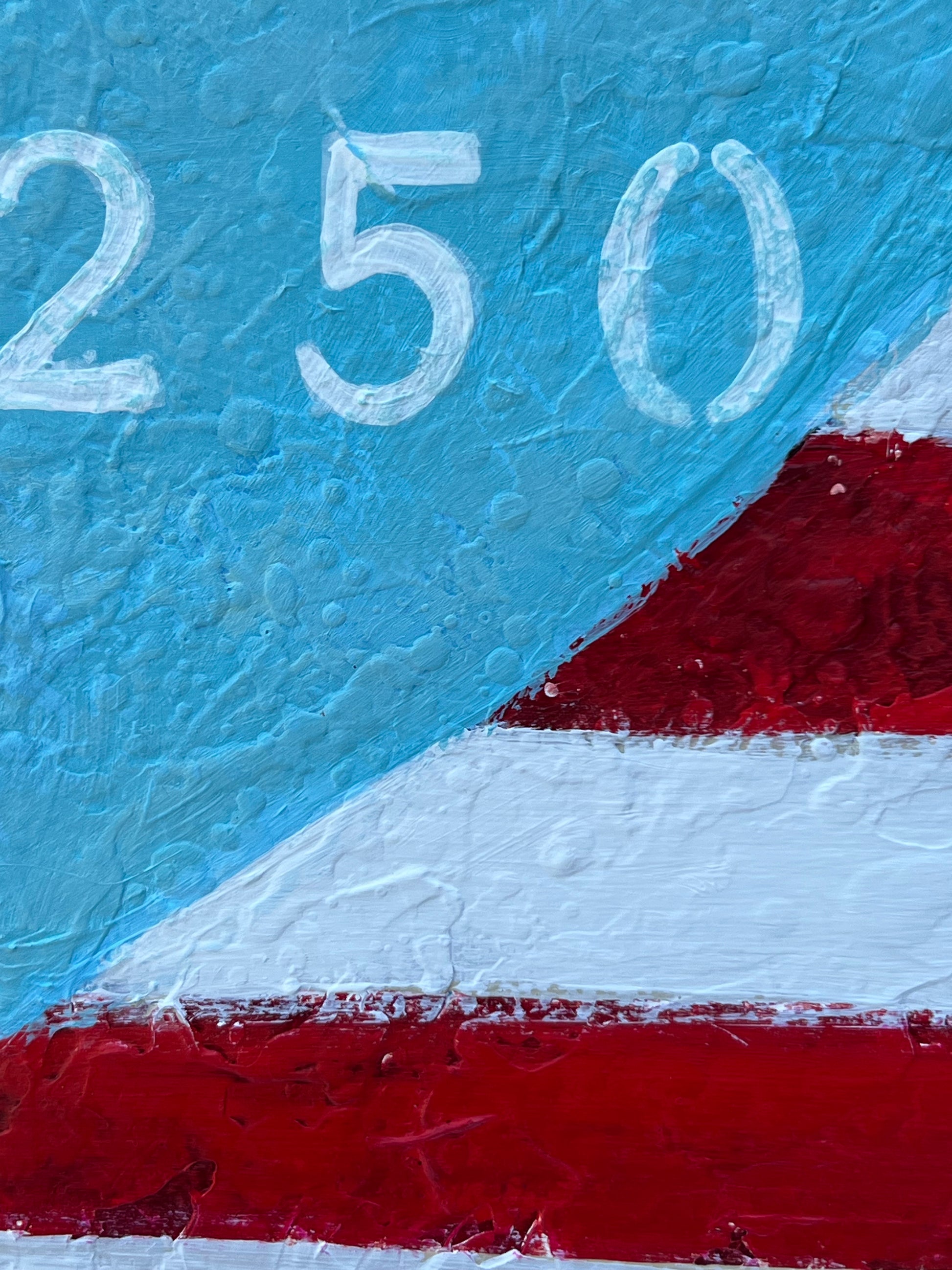 Close-up of a textured surface with '250' in white on a blue background, bordered by red and white.