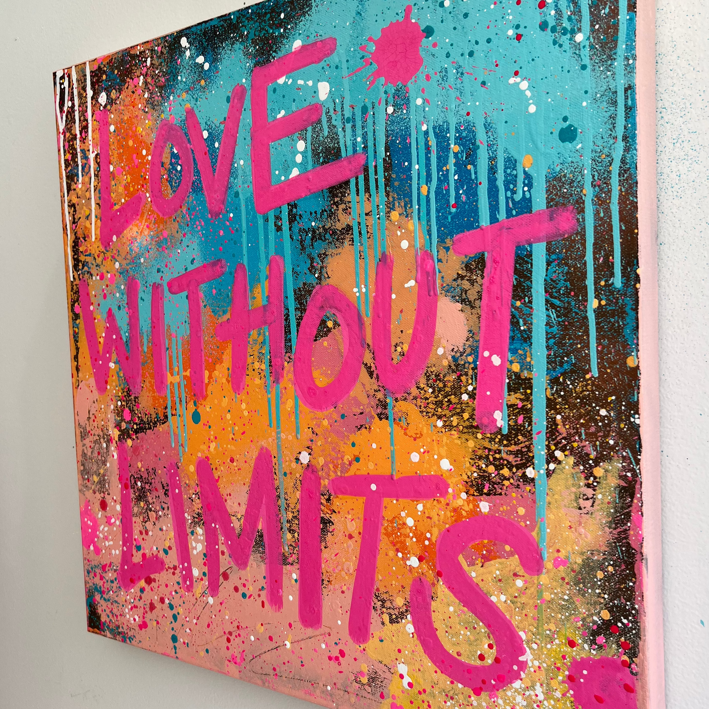 Colorful abstract painting with 'Love Without Limits' text on a white wall.